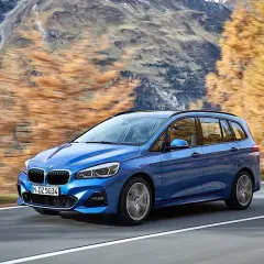 Niebieskie BMW 2 Gran Tourer jedzie po górskiej drodze jesienią.