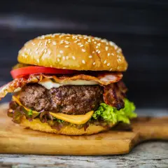 Soczysty burger z bekonem, serem, pomidorem i sałatą. Idealne dodatki do mięsa na burgery, by stworzyć taką ucztę.