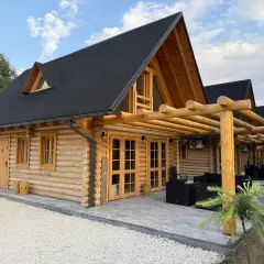 Drewniany dom z bali z werandą i meblami ogrodowymi.