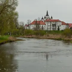 Malowniczy widok na Supraśl z rzeką w tle i klasztorem. Wiosna w pełni, zielone drzewa i krzewy.