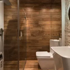 Moderno baño con ducha de cristal, paredes de madera y lavabo. ¿Cuánto cuesta cambiar bañera por plato de ducha?