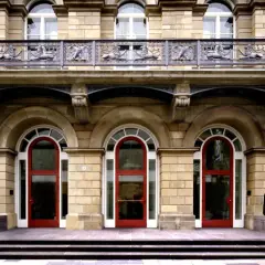 Vor dem Museum Wuppertal stehen zwei abstrakte Skulpturen. Die Fassade des Gebäudes ist aus hellem Stein, mit roten Türen und verzierten Balkonen.
