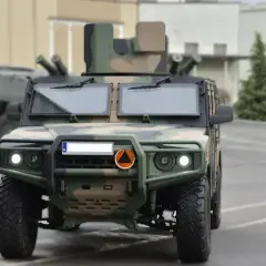 Polskie samochody wojskowe w kamuflażu, gotowe do akcji. Z przodu widać potężny pojazd z charakterystycznym grillem i światłami.