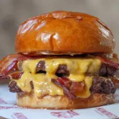 Jugosa hamburguesa doble con queso fundido y crujiente bacon, un festín que vale hundred Valencia.