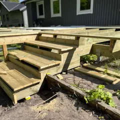 Nybyggd veranda i trä med trappsteg, redo att färdigställas.