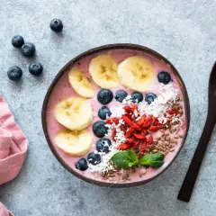 Kolorowa bowl z owocami: banan, borówki, jagody goji, wiórki kokosowe i siemię lniane. Idealna na zdrowe śniadanie, inspiracja z bowl przepisy.