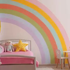 Pokój dziecięcy z pastelową tęczą na ścianie, łóżkiem i stolikiem. Inspiracja, jak namalować tęczę na ścianie.