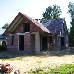 Budowa domu w toku, widoczne materiały budowlane i drabina. Może to być podstawa do obliczenia kary za samowolę budowlaną.