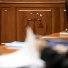 Drewniana ściana z symbolem wagi sprawiedliwości. Zastanawiasz się, ile trwa sprawa w sądzie cywilnym? Czas oczekiwania bywa różny.