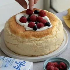 Deliciosa tarta de yogur griego esponjosa, decorada con frambuesas y arándanos frescos.