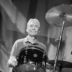 Charlie Watts, perkusista Rolling Stones, uśmiecha się za swoim zestawem perkusyjnym.