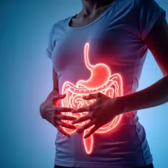 Kobieta trzyma się za brzuch, gdzie widoczny jest świecący na czerwono układ trawienny. Słychać niepokojące bulgotanie w brzuchu.