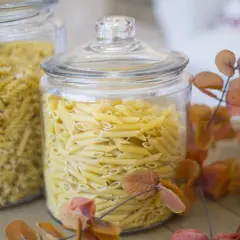 Zwei Glasbehälter voller Nudeln, Penne und Spiralen. Die Frage "wie lange sind nudeln haltbar" wird durch die frische Optik der ungekochten Pasta beantwortet.