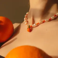 Collar de perlas y cuentas naranjas con un colgante de mandarina, como si fuera un sueño con naranjas.