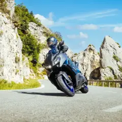 Motocyklista na sportowym motocyklu z power commanderem pokonuje zakręt na górskiej drodze, otoczony skalistymi zboczami i błękitnym niebem.