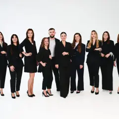 Grupa profesjonalistów w czarnych garniturach i sukienkach na białym tle.