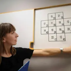 Kobieta wskazuje na tablicę z liczbami, która jest częścią testów psychologicznych dla kierowców z odpowiedziami.