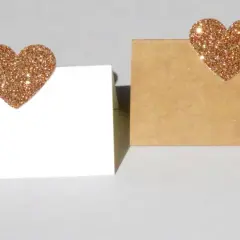 Segnaposto nozze d'oro fai da te: due cartoncini, uno bianco e uno kraft, decorati con cuori glitterati color oro.