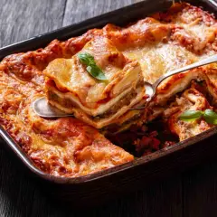 Pyszne lasagne z warzywami, zrumienione i pachnące, podane na drewnianym blacie. Idealne danie na rodzinny obiad.