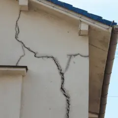 Duże pęknięcia na elewacji budynku sugerują, dlaczego dom osiada. Widoczne są ślady osiadania gruntu.