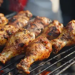 Grillade kycklingklubbor med kryddig jerk chicken-marinad som ryker på grillgallret.