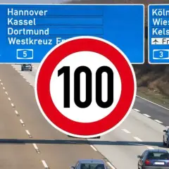 Znak ograniczenia prędkości do 100 km/h na niemieckiej autostradzie. W tle tablice z kierunkami do Hanoweru, Kolonii i Frankfurtu.