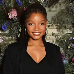 Halle Bailey ler mot kameran, omgiven av en blomsterinstallation.