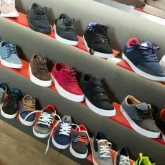 Scaffali pieni di sneakers, tra cui modelli nira rubens, in vari colori e stili, pronte per essere indossate.
