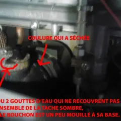 Détail d'une chaudière : une coulure sèche et une petite tache humide près d'un bouchon, peut-être la cause d'une veilleuse chauffage gaz ne tient pas.