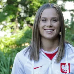 Uśmiechnięta Ewa Pajor, polska piłkarka, w białej bluzie z godłem Polski.