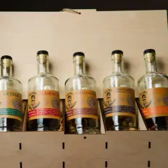 Pięć butelek nalewek w drewnianej skrzynce. Jaki spirytus do nalewek? Tu znajdziesz inspiracje: leśna, jesienna, orzechowa, czekoladowa i pomarańczowa.