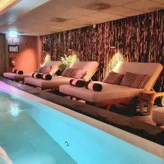 Avslappning vid poolen på ett elite hotell i Borlänge. Bekväma solstolar med kuddar och handdukar står redo vid det upplysta vattnet.