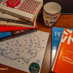 Książki i kubek z motywami Rumunii, w tym słownik polsko-rumuński, zachęcają do nauki języka rumuńskiego.