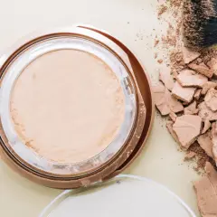 Rozsypany puder i pędzel do makijażu. Jak skleić cienie do powiek? Wskazówka: użyj alkoholu.