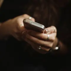 Dłonie z pierścionkami trzymają telefon, być może przeglądając oferty na OLX i myśląc o płatnościach PayPo.