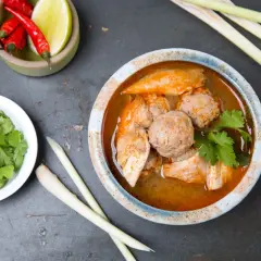 Aromatic tradycyjna zupa tajska z kurczakiem i klopsikami, podana z kolendrą, chili i trawą cytrynową.