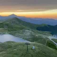 Alba sulle montagne toscane, con un lago alpino e rifugi che ricordano i borghi vicino Abetone.