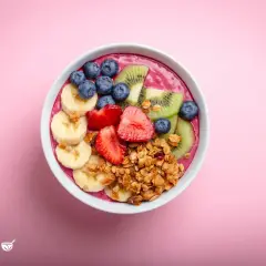 Eine bunte Acai Bowl mit Bananen, Erdbeeren, Blaubeeren und Kiwi, garniert mit Granola.