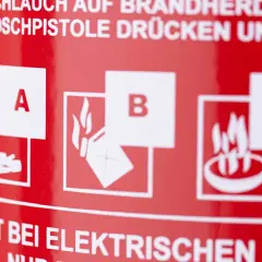 Symbole für Brandklasse A (feste Stoffe), B (flüssige Stoffe) und F (Fettbrände) auf rotem Feuerlöscher.