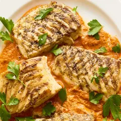 Filetes de bacalao a la parrilla con salsa de pimientos rojos y perejil fresco. Un plato principal perfecto para tus recetas de bacalao.