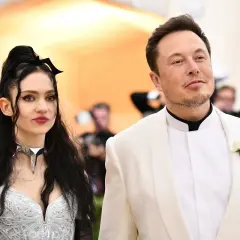 Grimes i Elon Musk na czerwonym dywanie. Ona w srebrnej kreacji z nietypowym naszyjnikiem, on w białej marynarce.
