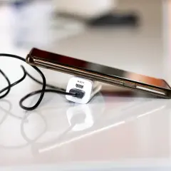 Smartfon podłączony do ładowarki, by zapobiec nadmiernemu zużyciu baterii.