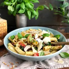 En läcker pastasallad med pesto, soltorkade tomater och färsk basilika, toppad med parmesan.