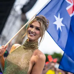 Uśmiechnięta kobieta z flagą Australii, dumna reprezentacja kraju na Eurowizji.