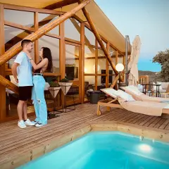 Pareja disfrutando de la tranquilidad de la dehesa experiences, con piscina y tumbonas en una cabaña de madera.