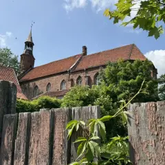 Stary, drewniany płot i ceglany kościół z wieżą w malowniczym mieście na Kociewiu.