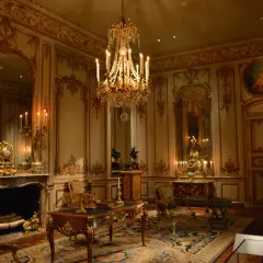 A lavish room with a crystal chandelier, ornate gold trim, and antique furniture embodies the royalcore aesthetic.