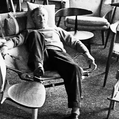 Hans J Wegner, a master of Danish design, relaxes amidst his iconic chairs, surrounded by his timeless creations.
