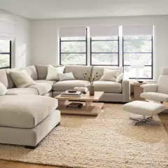 A large, neutral sectional couch is arranged in a cozy living room, showcasing different ways to arrange a sectional couch for optimal comfort and style.