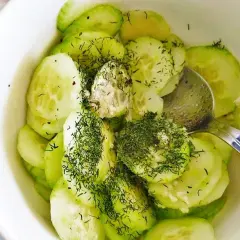 Świeża surówka z ogórka, posypana obficie koperkiem, w białej miseczce. Idealna na letni obiad.